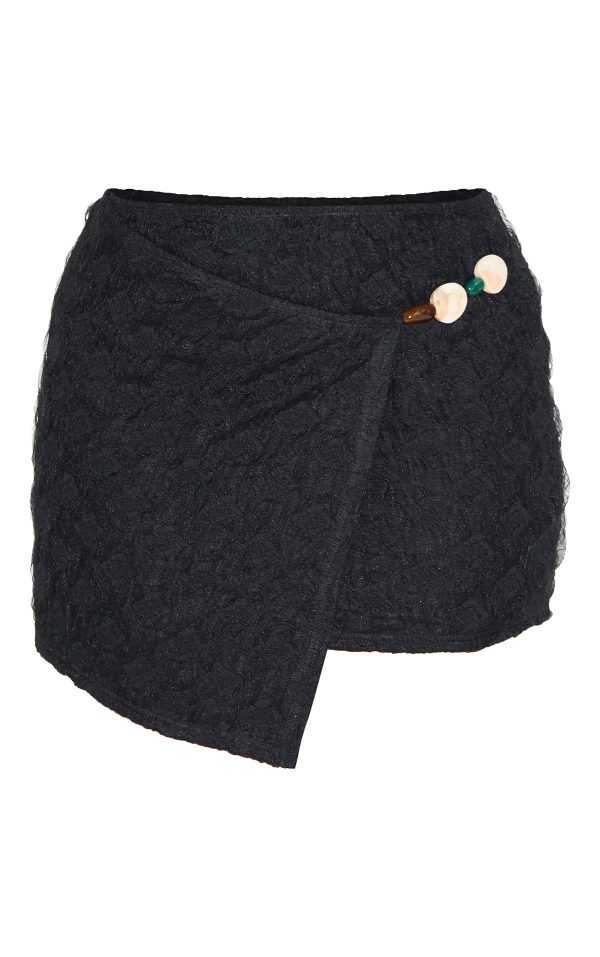 1059356e5ddfad6e8183e7d955131e8ad7ddd5cc_CNM6457_6_shape_black_textured_wrap_over_beaded_trim_mini_skirt