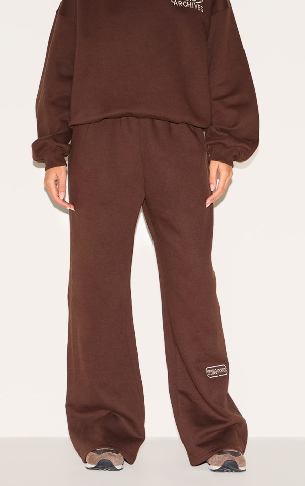 76056dcce57ee53ebb118fc4fb539908bfe0f337_CNM4805_2_chocolate_studio_archives_embroidered_thin_waistband_drop_crotch_joggers