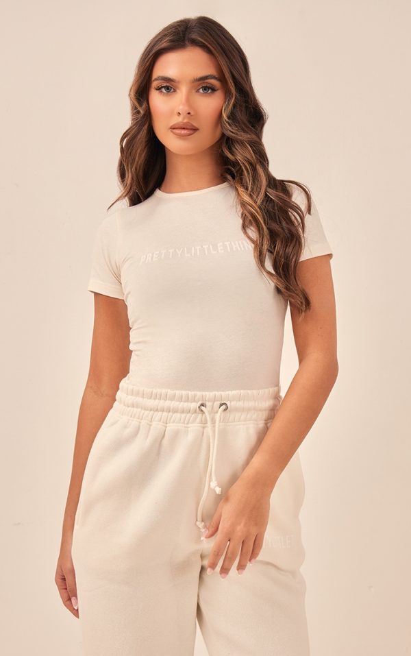 9397d2b051823ceb18be8e7d4a6bad0c17aadb00_CNF2372_1_prettylittlething_off_white_logo_short_sleeved_bodysuit
