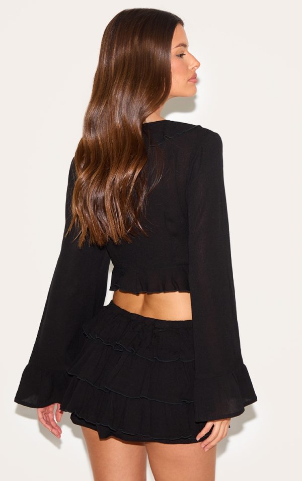 ad8cd1c6b912ef70433facbabd0e6150caceded5_CNM3228_2_black_cheesecloth_ruffle_tie_front_long_sleeve_top